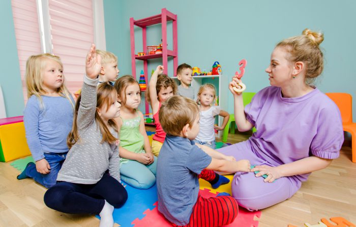 Lovely preschoolers listening young teacher very carefully English Time - nauka język angielski